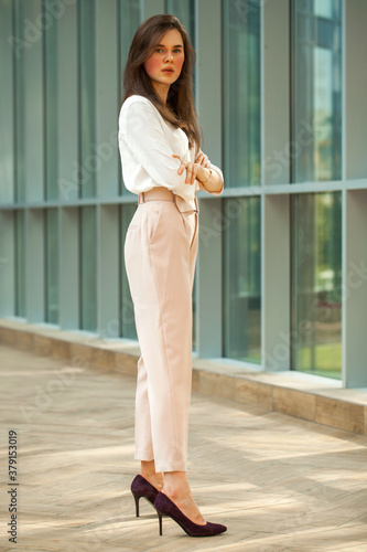 Young beautiful brunette woman in white blouse and pink pants in office