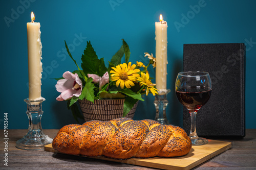 Shabbat Shalom. Challah bread, shabbat wine and candles on wooden table. Lighting a candle photo