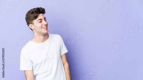 Young caucasian man isolated on purple background relaxed and happy laughing, neck stretched showing teeth. © Asier