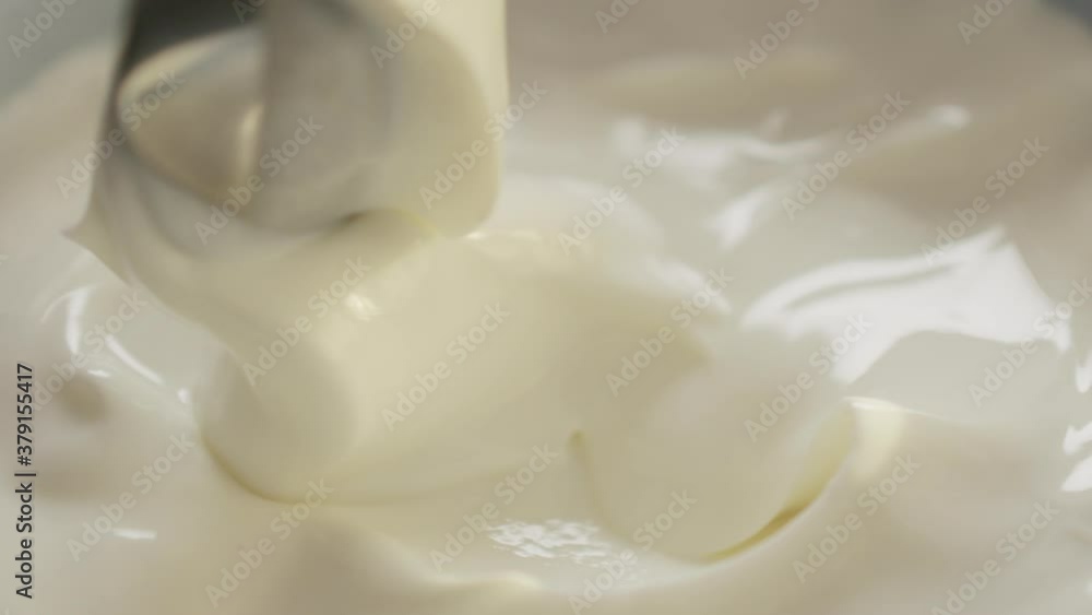 Slow motion swirl white yogurt with spoon closeup Slow motion swirl white yogurt with spoon closeup