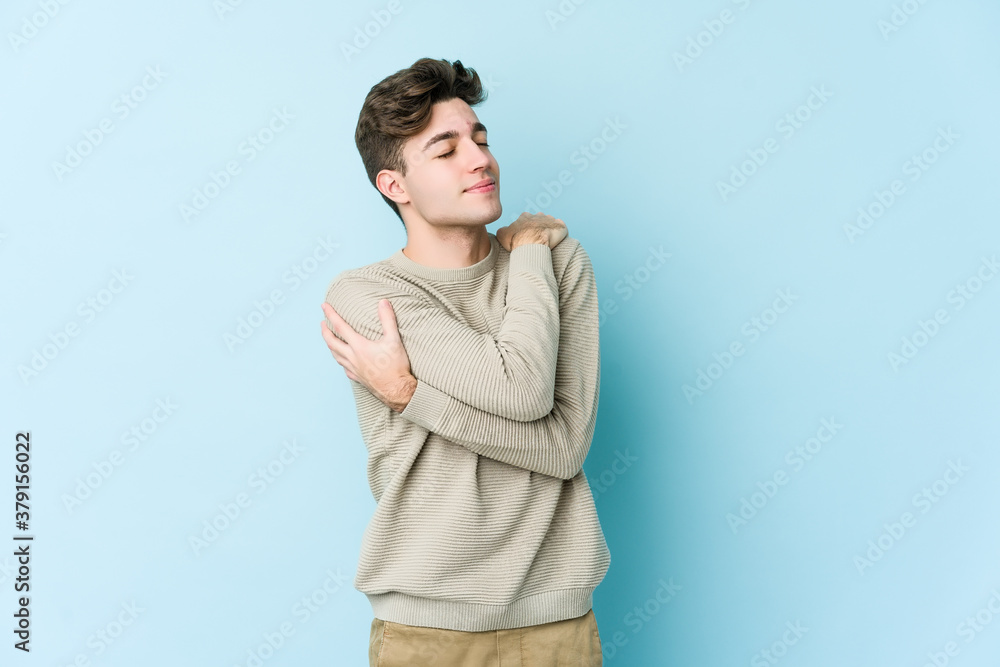 Young caucasian man isolated on blue background hugs, smiling carefree and happy. Young caucasian man isolated on blue background hugs, smiling carefree and happy.
