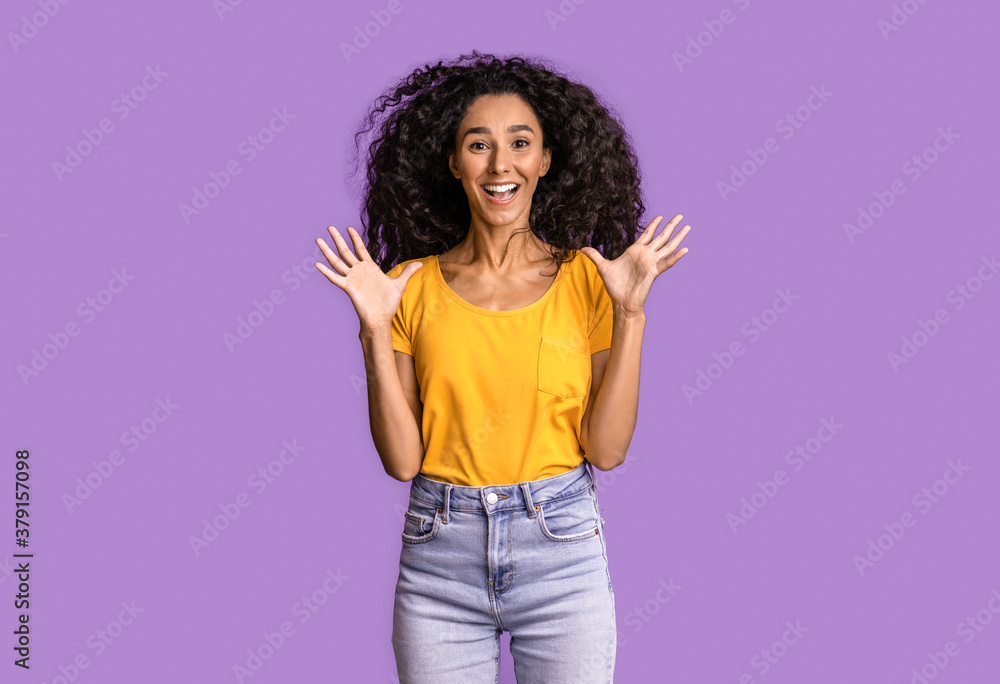 Excited joyful brunette lady jumping with raised hands over purple background Excited joyful brunette lady jumping with raised hands over purple background