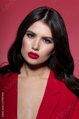 Beautiful sexy brunette woman face cosmetic makeup wear red suit  looking angry at camera  over red background.