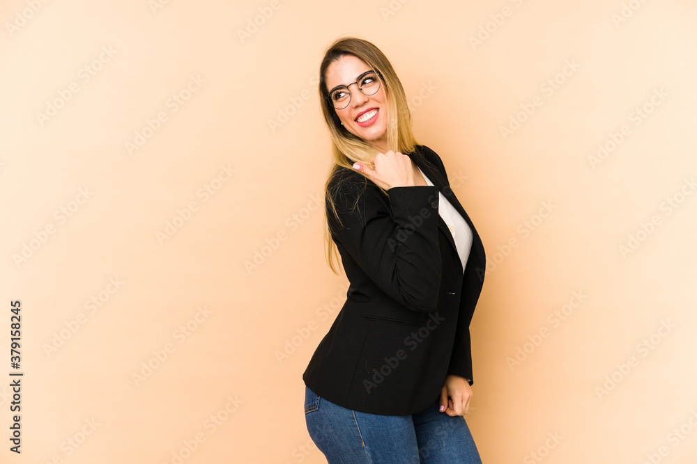 Middle age business woman isolated on beige background points with thumb finger away, laughing and carefree. Middle age business woman isolated on beige background points with thumb finger away, laughing and carefree.