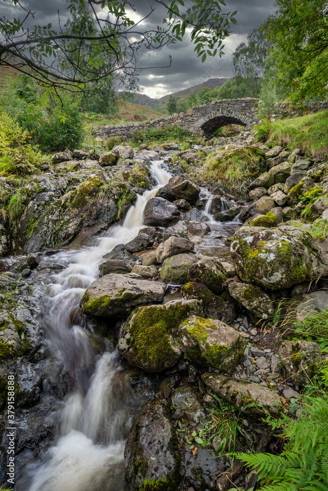 Stunning long exposure landscape image of Ashness Bridge in English Lake District during late Summer afternoon with dramatic lighting Stunning long exposure landscape image of Ashness Bridge in English Lake District during late Summer afternoon with dramatic lighting