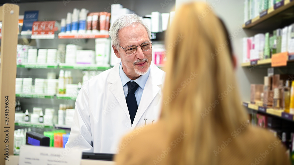 Senior pharmacist dealing with a customer Senior pharmacist dealing with a customer