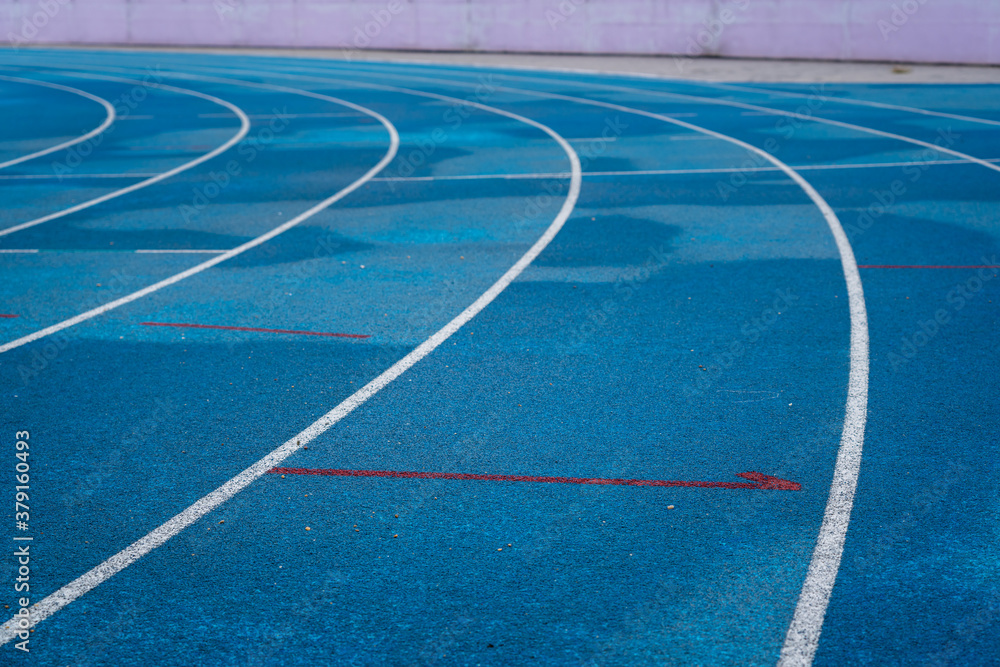 Professional running track of blue rubber surface with standard line, sport background photo. Close-up and selective focus.