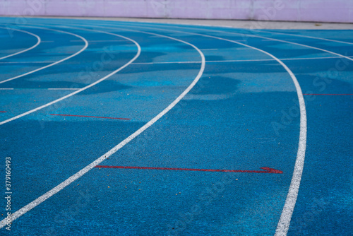Professional running track of blue rubber surface with standard line  sport background photo. Close-up and selective focus.