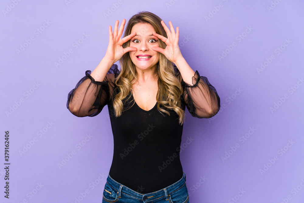 Young caucasian woman isolated on purple background keeping eyes opened to find a success opportunity. Young caucasian woman isolated on purple background keeping eyes opened to find a success opportunity.