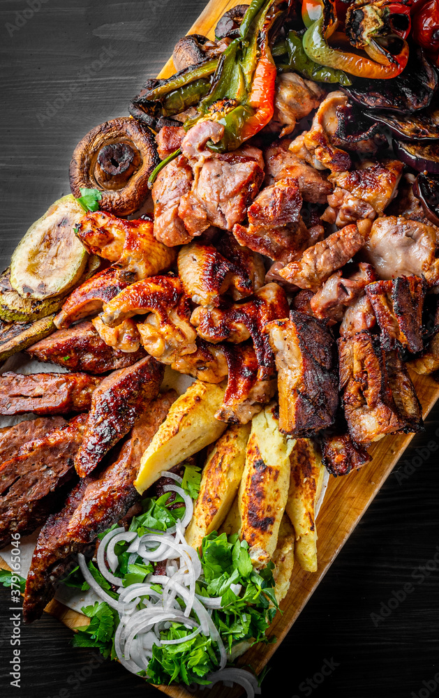 Assorted Mixed different grilled meat with vegetables on table Assorted Mixed different grilled meat with vegetables on table