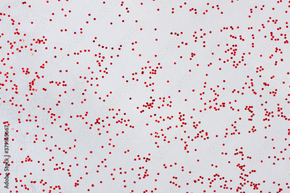 Red confetti on grey background. Christmas, winter, new year texture. Flat lay, top view