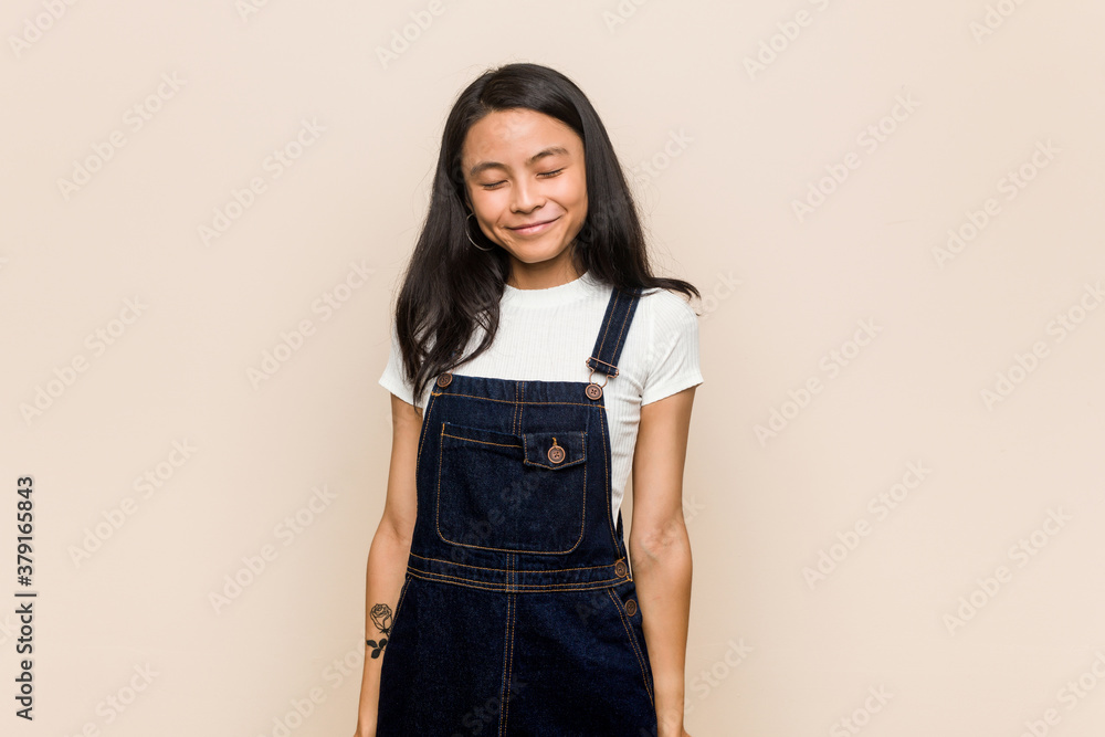 Young cute chinese teenager Young blonde woman wearing a coat against a pink background laughs and closes eyes, feels relaxed and happy. Young cute chinese teenager Young blonde woman wearing a coat against a pink background laughs and closes eyes, feels relaxed and happy.