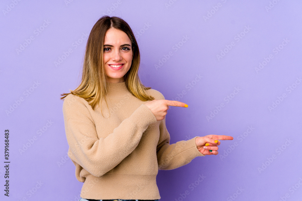 Young caucasian woman isolated on purple background shocked pointing with index fingers to a copy space. Young caucasian woman isolated on purple background shocked pointing with index fingers to a copy space.