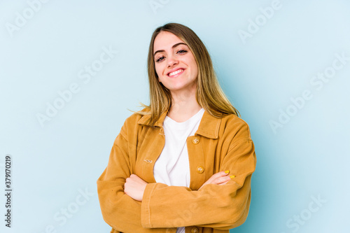 Young caucasian woman isolated on blue background who feels confident, crossing arms with determination.
