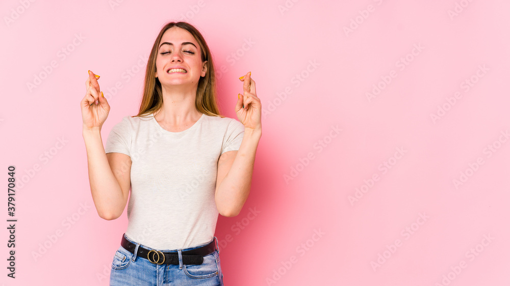 Young caucasian woman isolated on pink background crossing fingers for having luck Young caucasian woman isolated on pink background crossing fingers for having luck