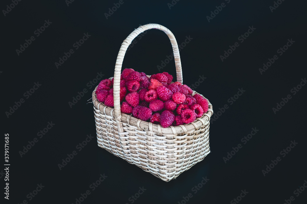 Ripe raspberries in a white wicker basket on a black background. Ripe raspberries in a white wicker basket on a black background.