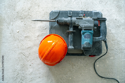 Dismantling works background. Rotary hammer for construction destroying and hardhat on the concrete. Real working atmosphere. photo