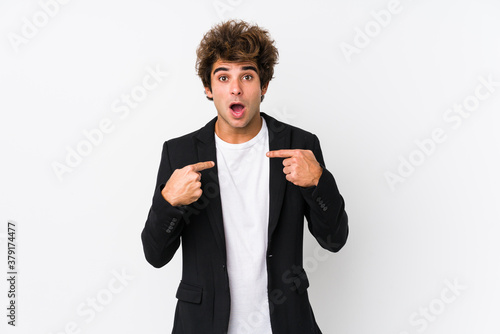 Young caucasian business man against a white background isolated surprised pointing with finger, smiling broadly.