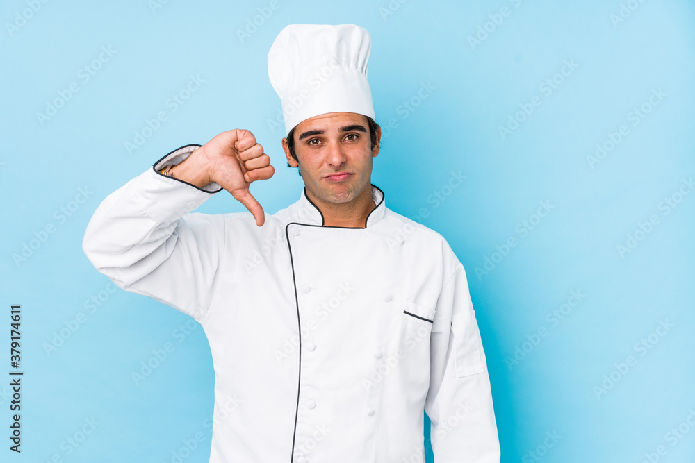 Young cook man isolated showing a dislike gesture, thumbs down. Disagreement concept. Young cook man isolated showing a dislike gesture, thumbs down. Disagreement concept.