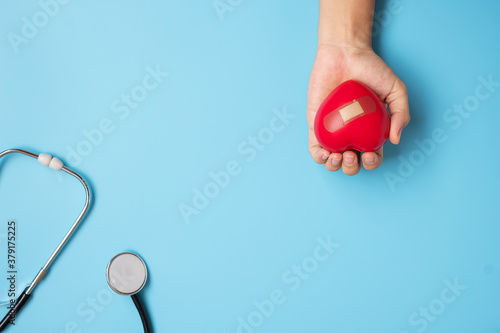 Doctor hand holding Red heart shape with Stethoscope on blue background. Healthcare, life Insurance and World Heart Day concept