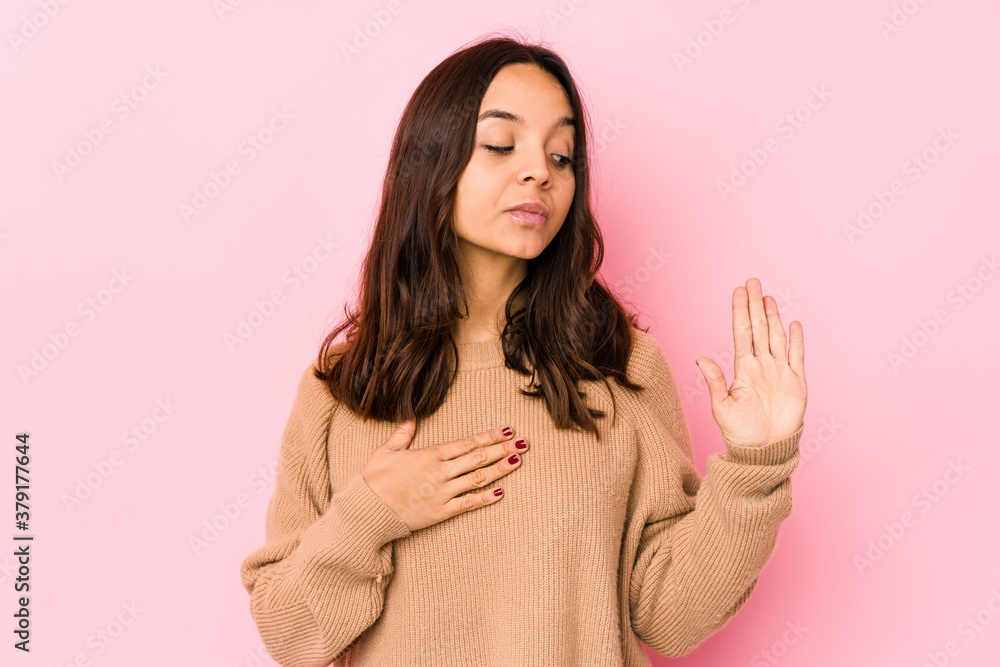 Young mixed race hispanic woman isolated taking an oath, putting hand on chest. Young mixed race hispanic woman isolated taking an oath, putting hand on chest.
