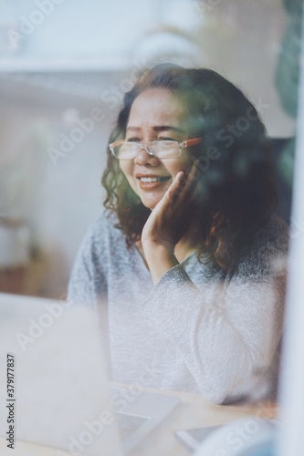 Elderly Asian woman using laptop  in living room.