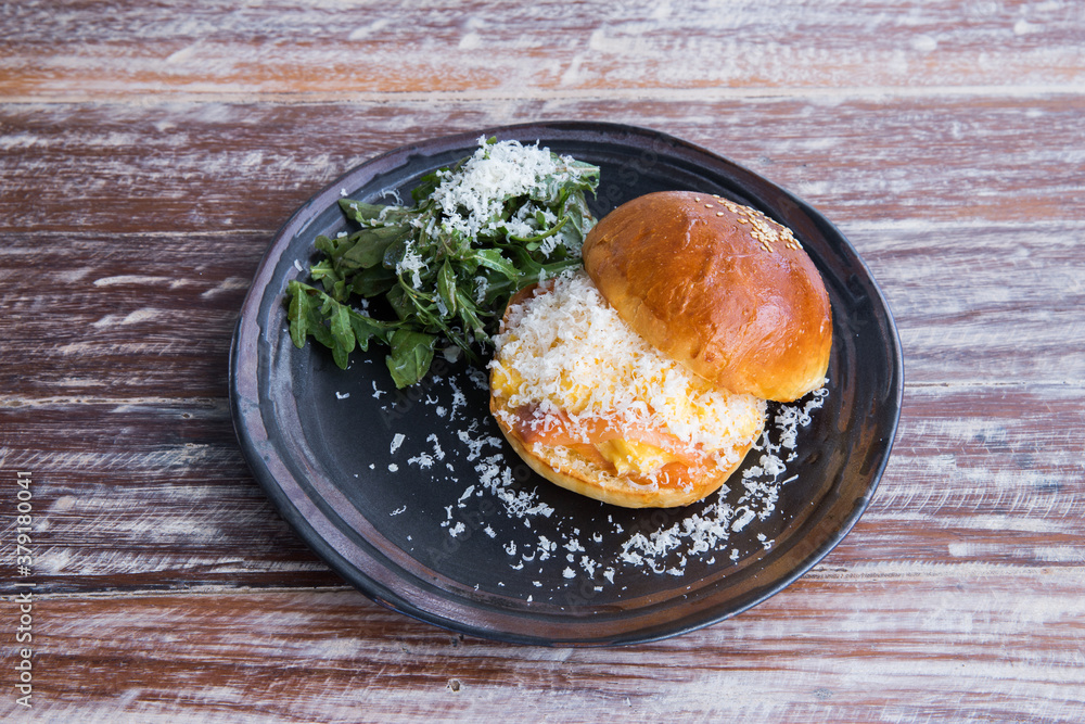 salmon cheese burger in black plate on wood dining table.