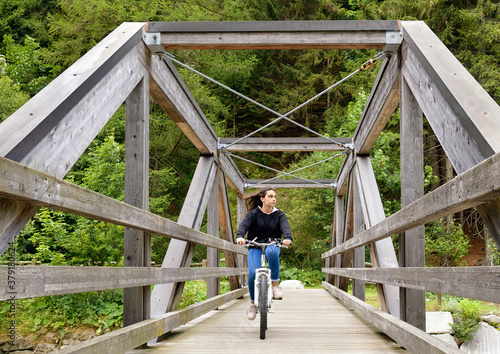 Young girl riding her bicycle across a bridge