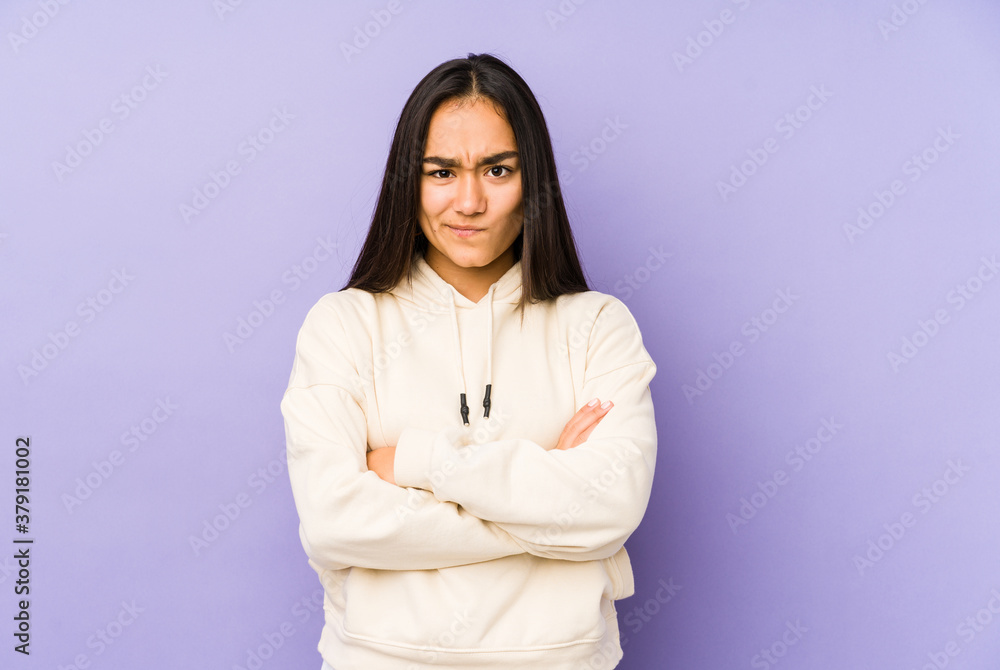 Young woman isolated on a purple background frowning face in displeasure, keeps arms folded. Young woman isolated on a purple background frowning face in displeasure, keeps arms folded.