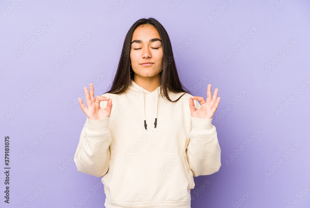 Young woman isolated on a purple background relaxes after hard working day, she is performing yoga. Young woman isolated on a purple background relaxes after hard working day, she is performing yoga.