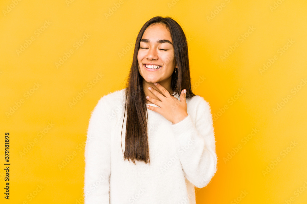 Young woman isolated on a yellow background laughs out loudly keeping hand on chest. Young woman isolated on a yellow background laughs out loudly keeping hand on chest.