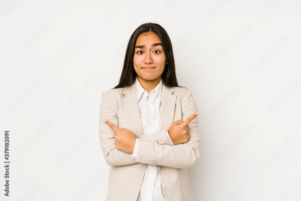 Young woman isolated on a white background points sideways, is trying to choose between two options. Young woman isolated on a white background points sideways, is trying to choose between two options.