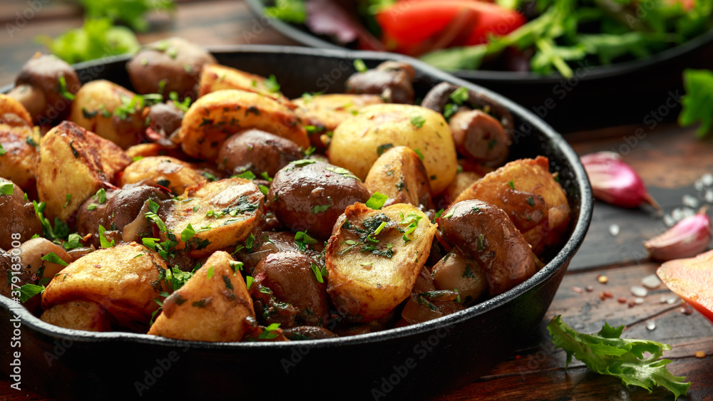 Baked potato with mushrooms and herbs in iron cast pan on wooden table Baked potato with mushrooms and herbs in iron cast pan on wooden table