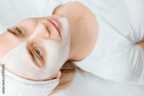 Female with healthy glow perfect smooth skin. Young woman getting spa treatment at beauty salon. Skincare concept. Girl enjoys cream facial mask.