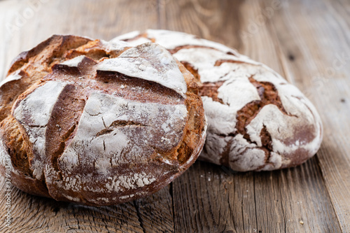 Gold rustic crusty loaves of bread and buns on wooden background. Still life captured from above top view, flat lay.