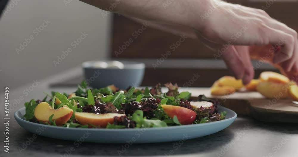 Slow motion man making salad with nectarines and mozzarella on a blue plate on concrete countertop on kitchen, add nectarines Slow motion man making salad with nectarines and mozzarella on a blue plate on concrete countertop on kitchen, add nectarines