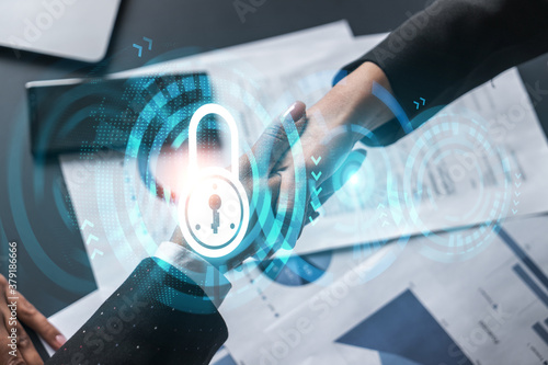 Фотография Multiexposure of two businesspeople handshake and lock icon hologram drawing background