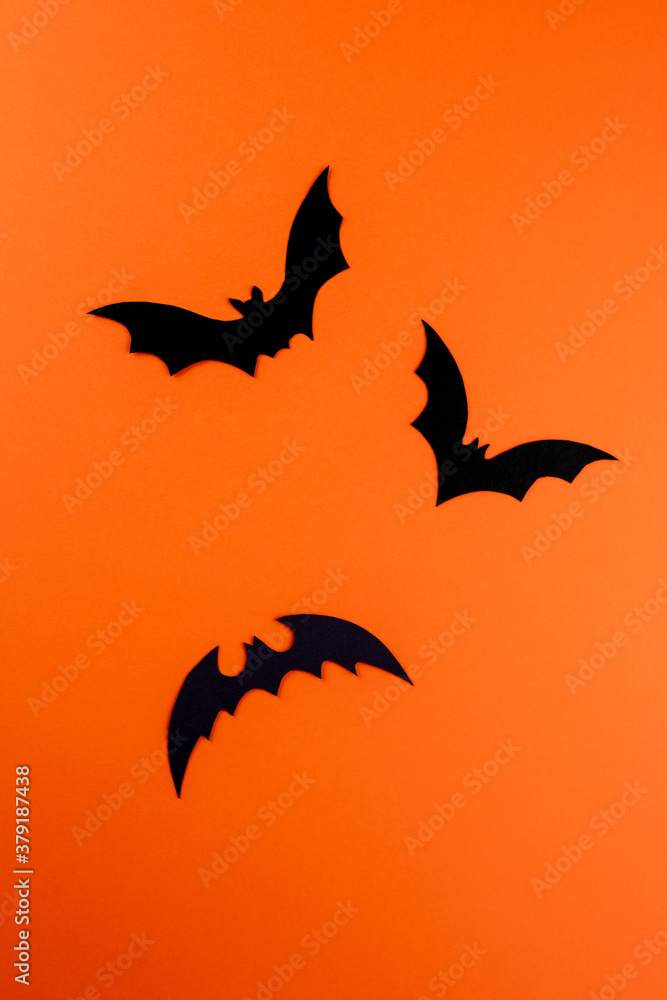 Fototapeta premium Three black paper bats on orange background