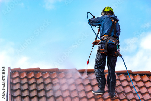 worker washing the roof with pressurized water