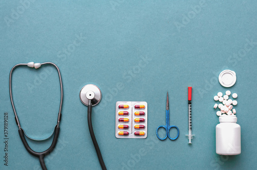 Pills, ampoule, syringes, capsules, stethoscope on the blue doctor s table.