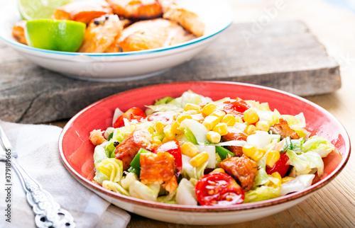 Fresh salad with grilled salmon on table.