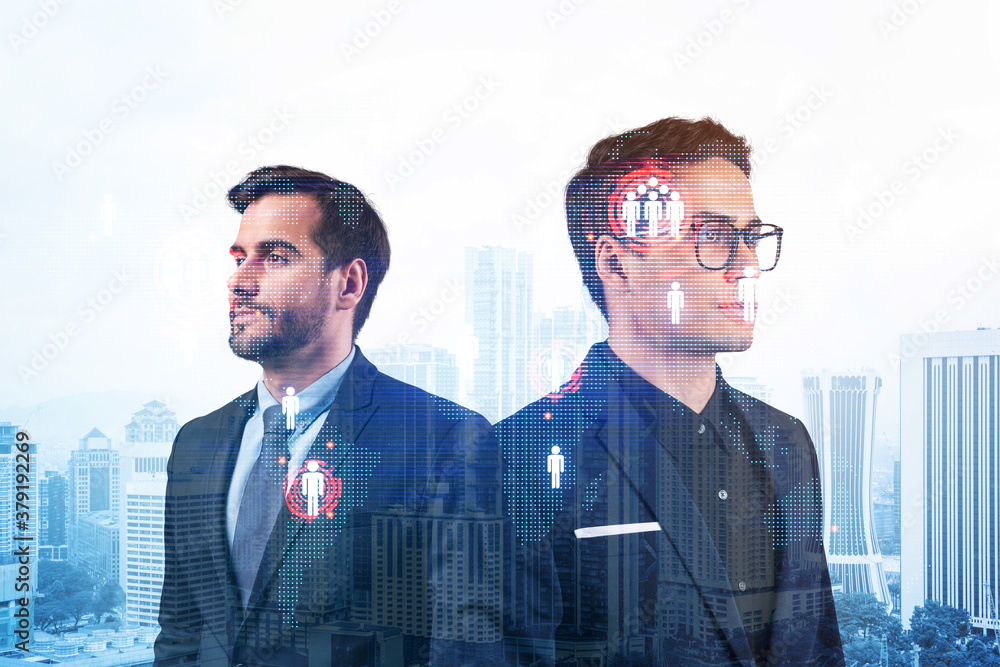 Fototapeta premium Two handsome young SMM specialists thinking about development of social media marketing strategy to achieve business goals. Hologram icons over Kuala Lumpur background.