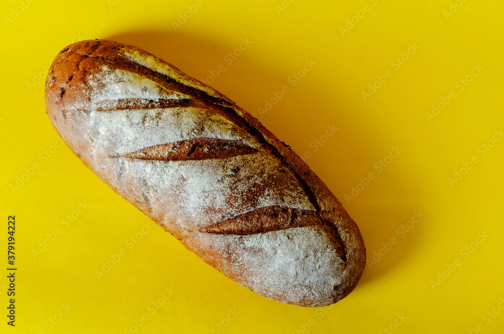 A loaf of freshly baked rye bread on a yellow background. A loaf of freshly baked rye bread on a yellow background.