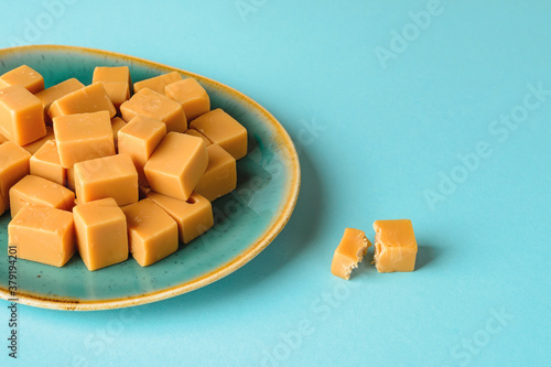 Konstfotografi Close-up of caramel vanilla fudge on a turquoise ceramic plate over turquoise background