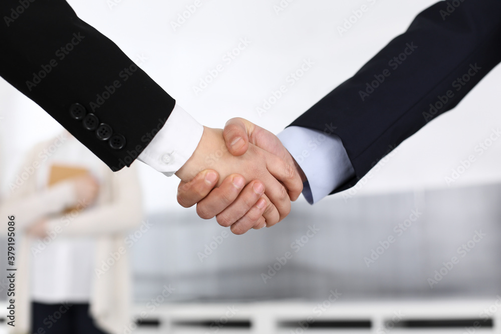 Businessman and woman shaking hands in office. Concept of handshake as success symbol in business Businessman and woman shaking hands in office. Concept of handshake as success symbol in business