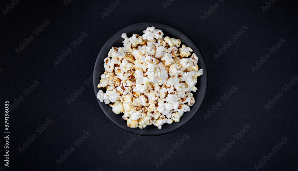Scattered salted popcorn in a bowl on black background with copy space. Homemade Popcorn Top view. . Scattered salted popcorn in a bowl on black background with copy space. Homemade Popcorn Top view. .