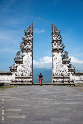 Hindu Lempuyang temple gates Instagram famous location for tourists taking solo photograph wearing Sarong with blue background sky