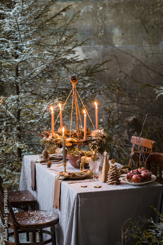 Table served for Christmas dinner, festive setting with decorations, burning candles and fir-tree branches