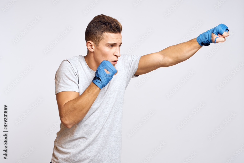 sporty male boxer in blue gloves practicing punches on a light background cropped view sporty male boxer in blue gloves practicing punches on a light background cropped view