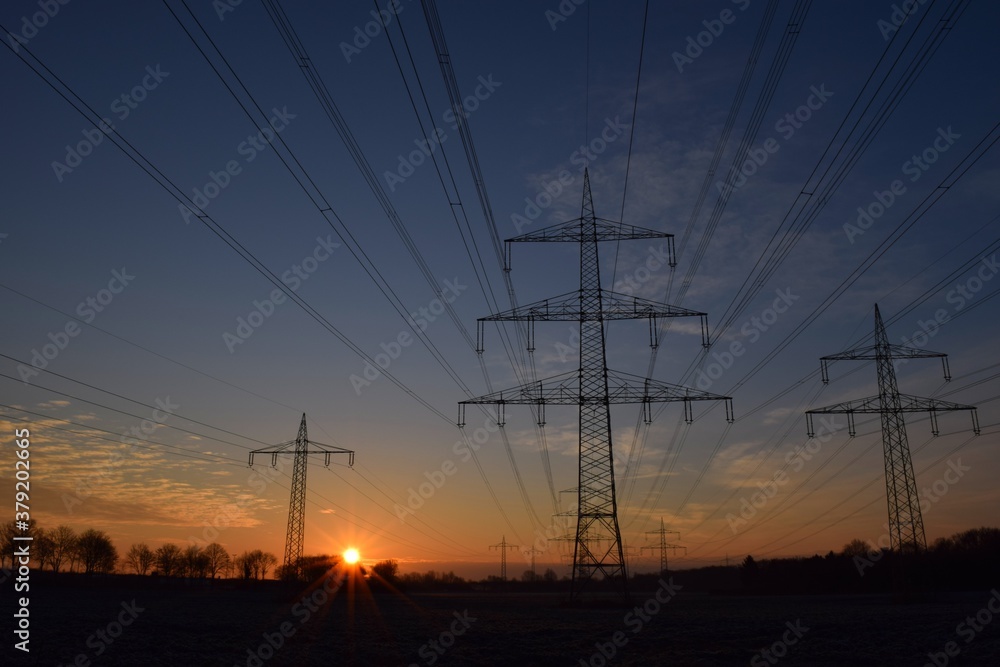 Sonnenaufgang an einem Feld mit Strommasten